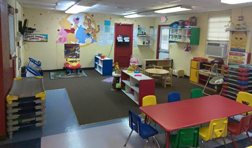 Playroom with small tables and chairs, shelves, and cots