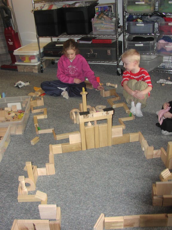 Child and teen playing with wooden blocks on the floor