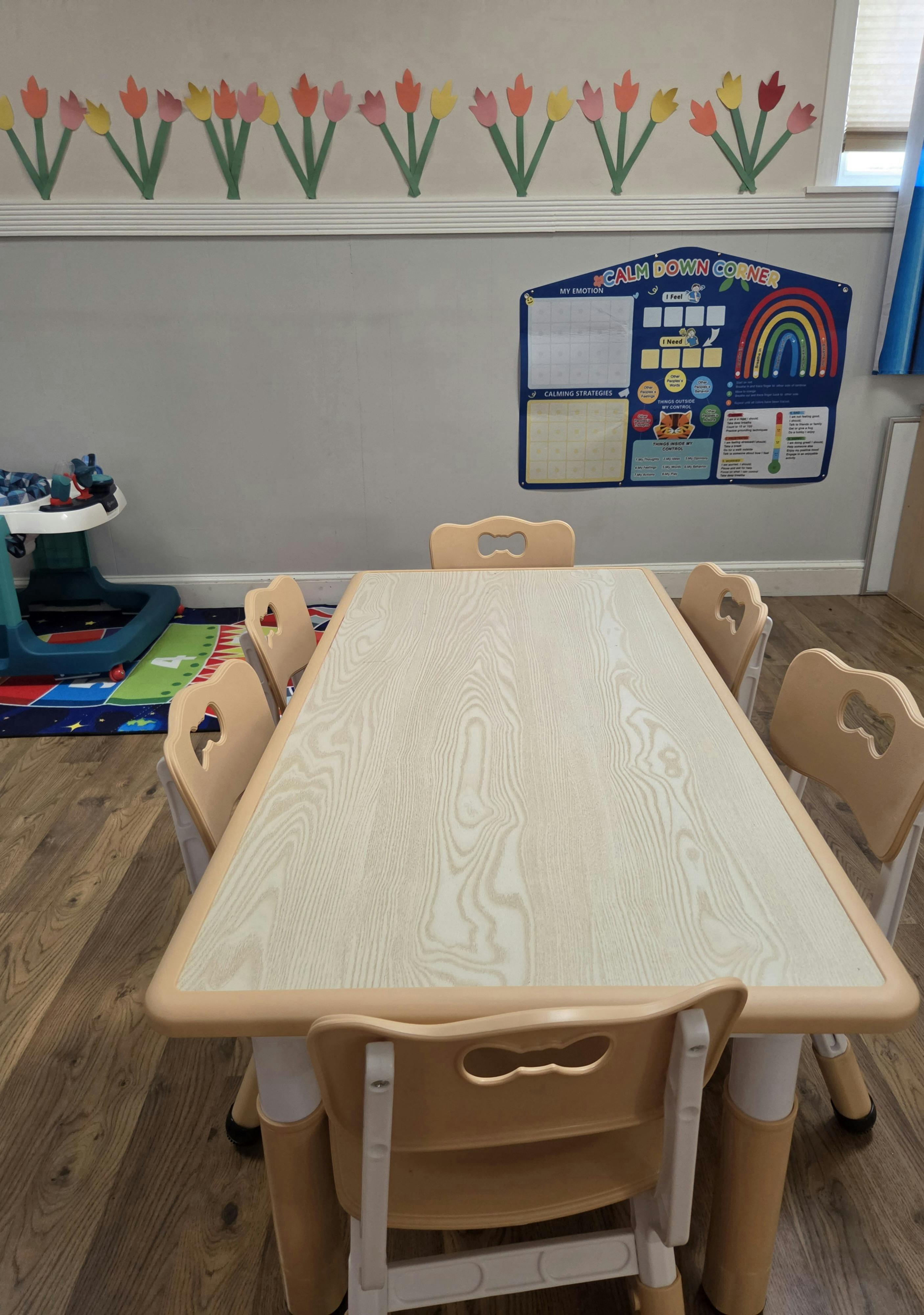 Child-sized table and chairs in a classroom with a calm down corner poster