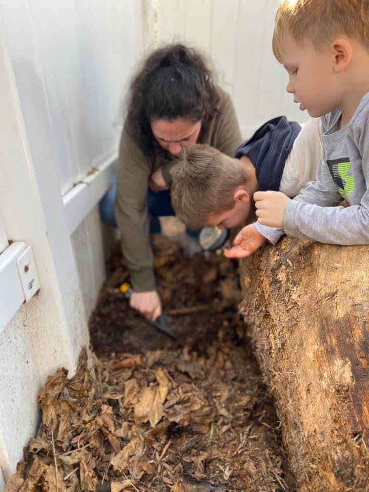 Person and two children looking at leaves and dirt