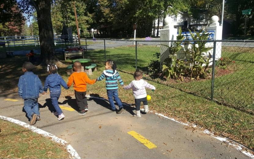 Group of children holding hands while walking on a painted path at a playground