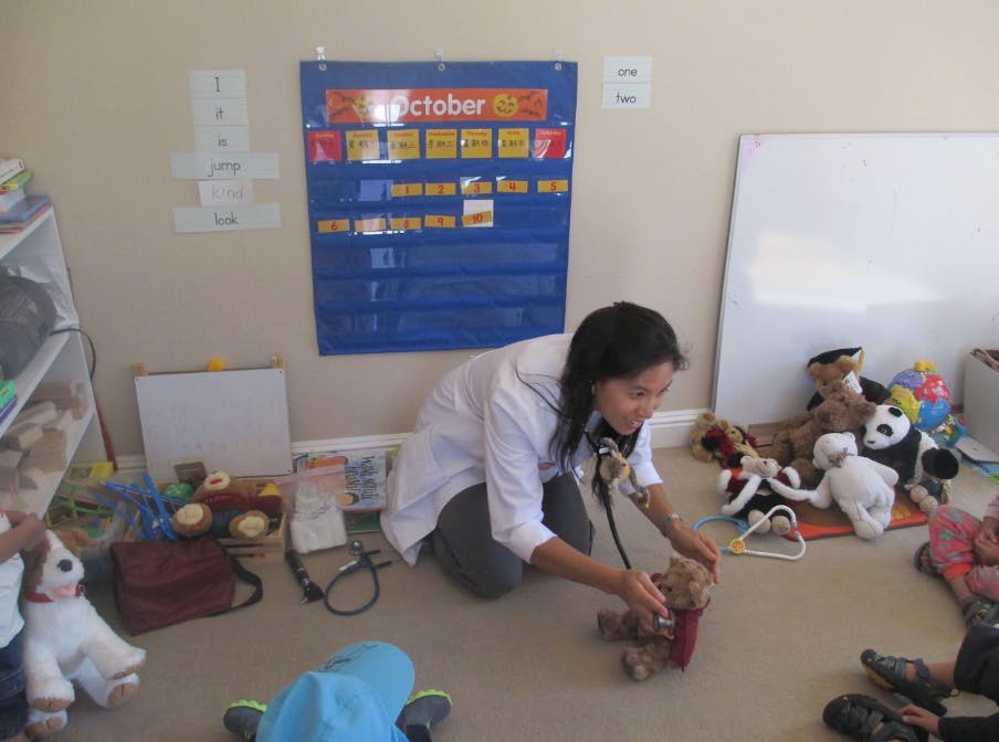 Person in lab coat using stethoscope on a teddy bear