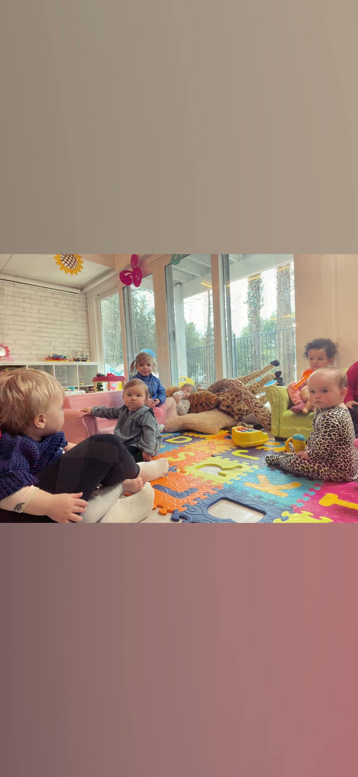Multiple children playing on a colorful mat indoors