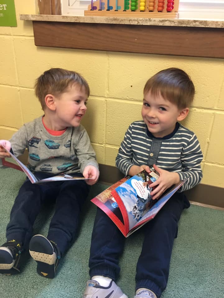 Two children sitting on the floor reading books