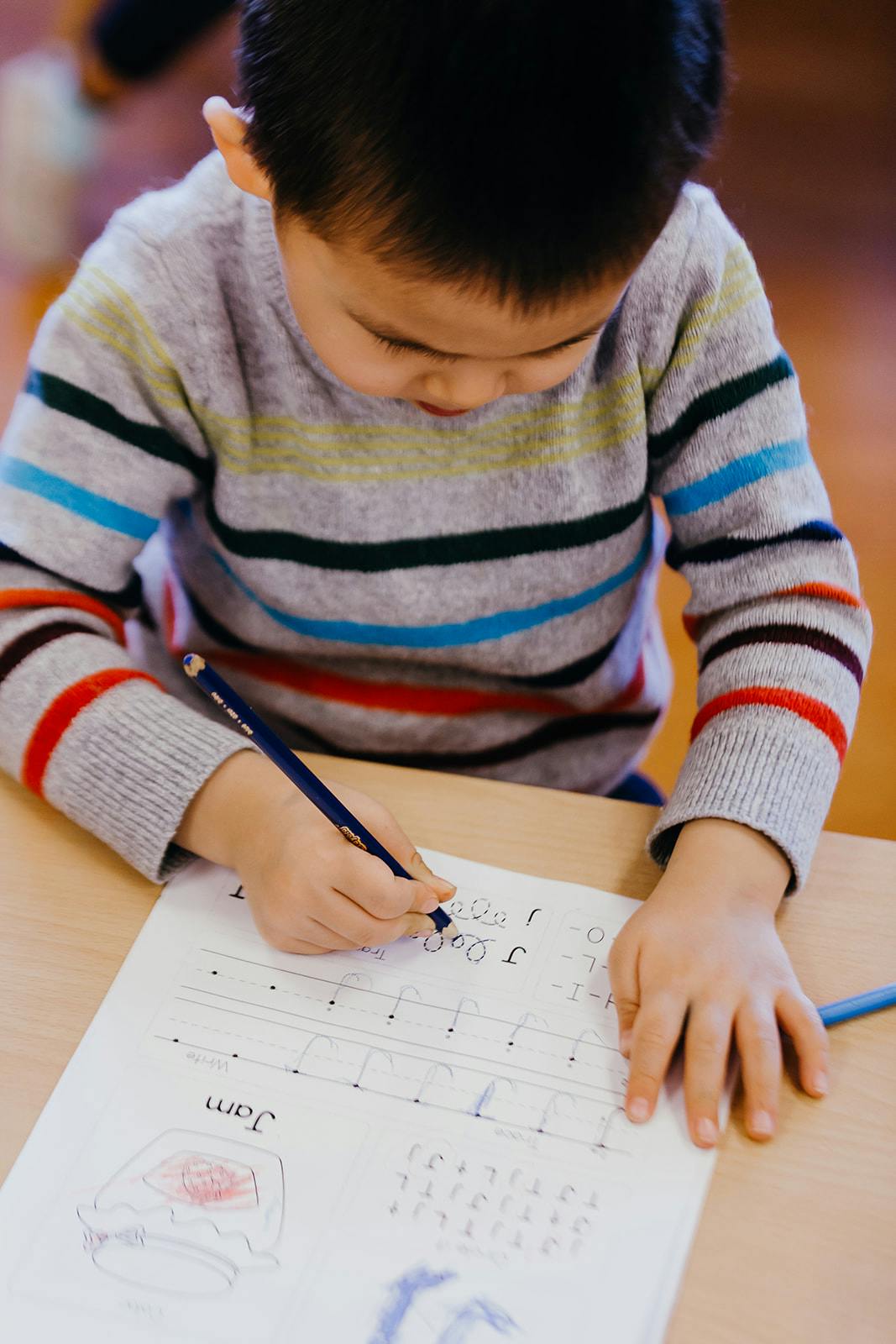 Child writing on a worksheet with a pencil