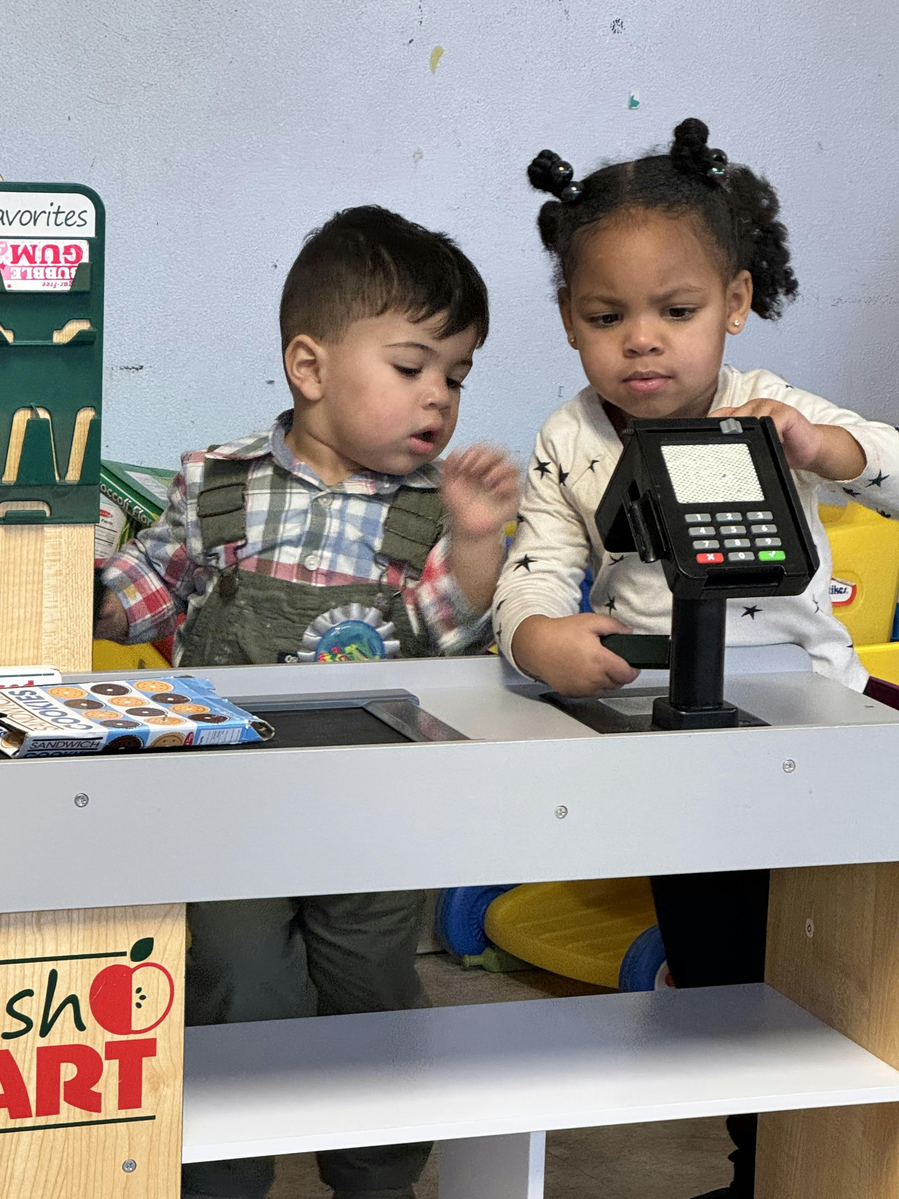 Two children playing with a toy cash register