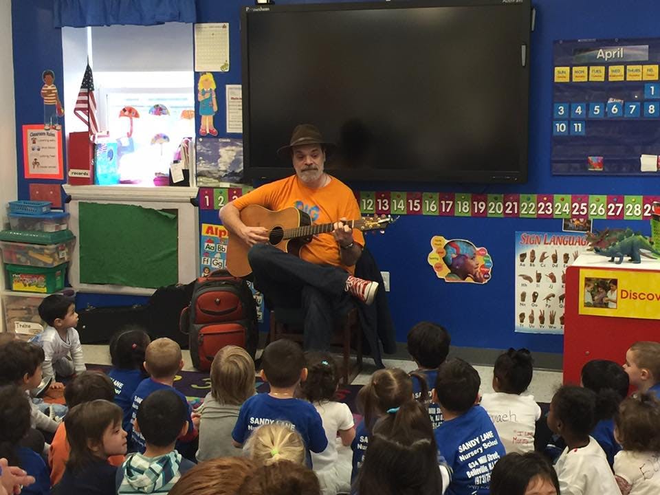 Person playing guitar for children in a classroom