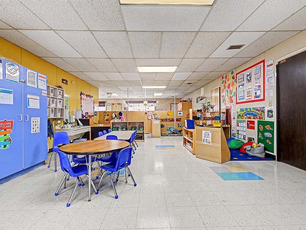 Classroom with small tables and chairs, cubbies, and colorful decorations