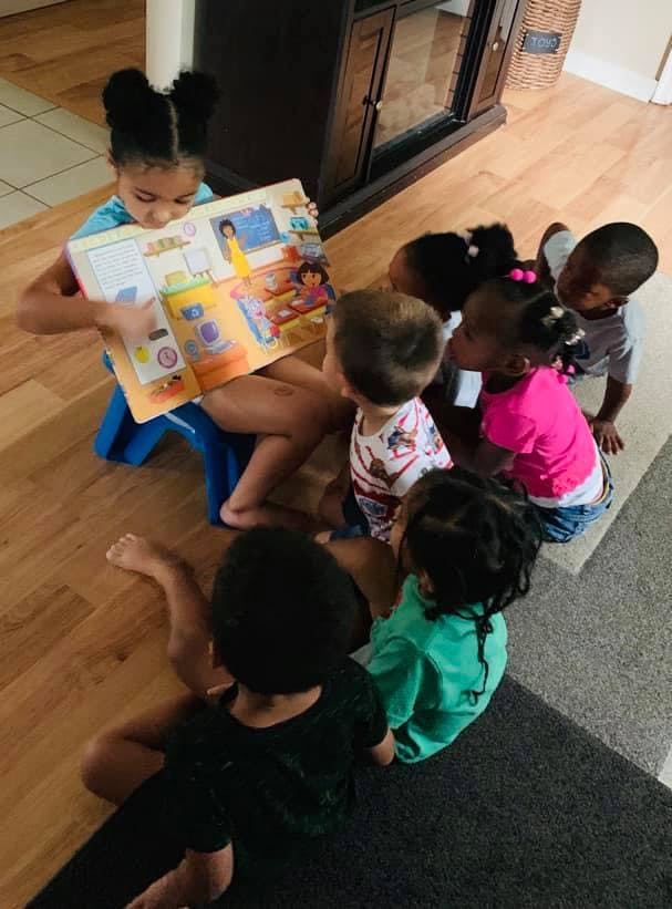 Child reading a book to a group of children