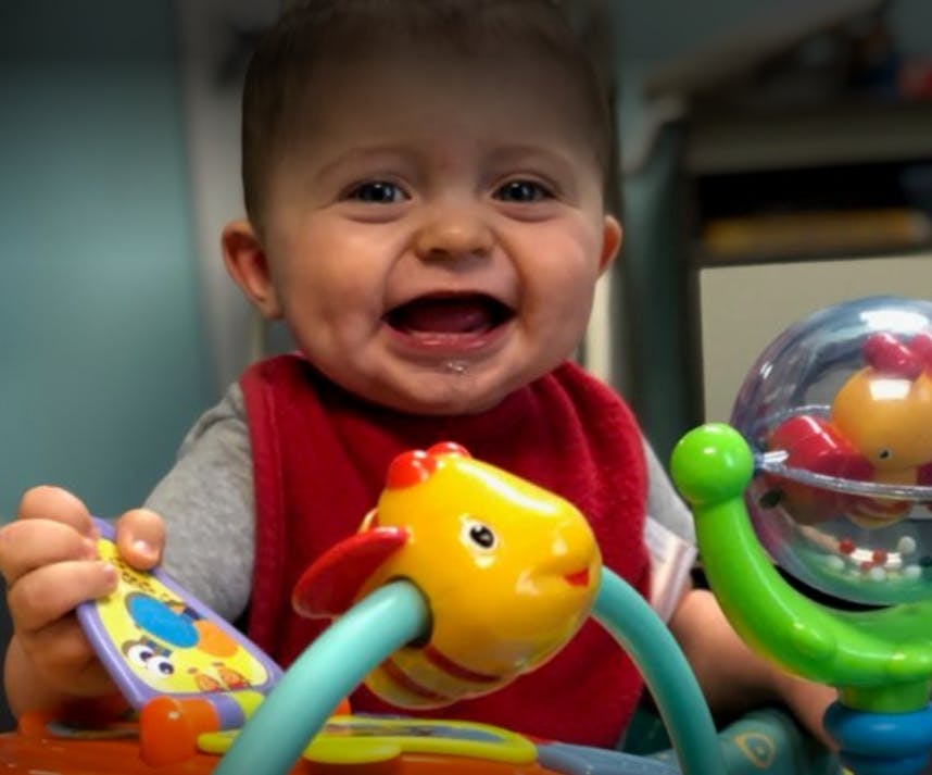 Child in a red bib playing with colorful toys