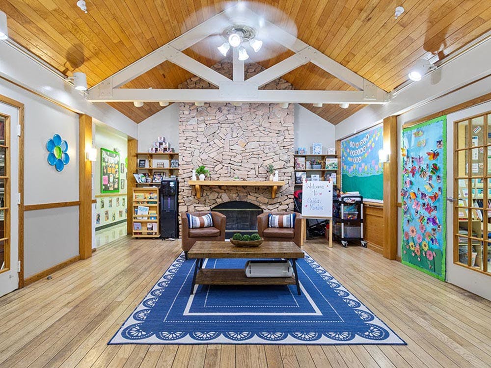 Lounge area with a stone fireplace, blue rug, and wooden ceiling