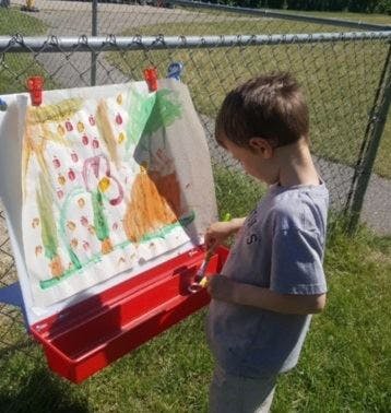 Child painting outdoors on an easel