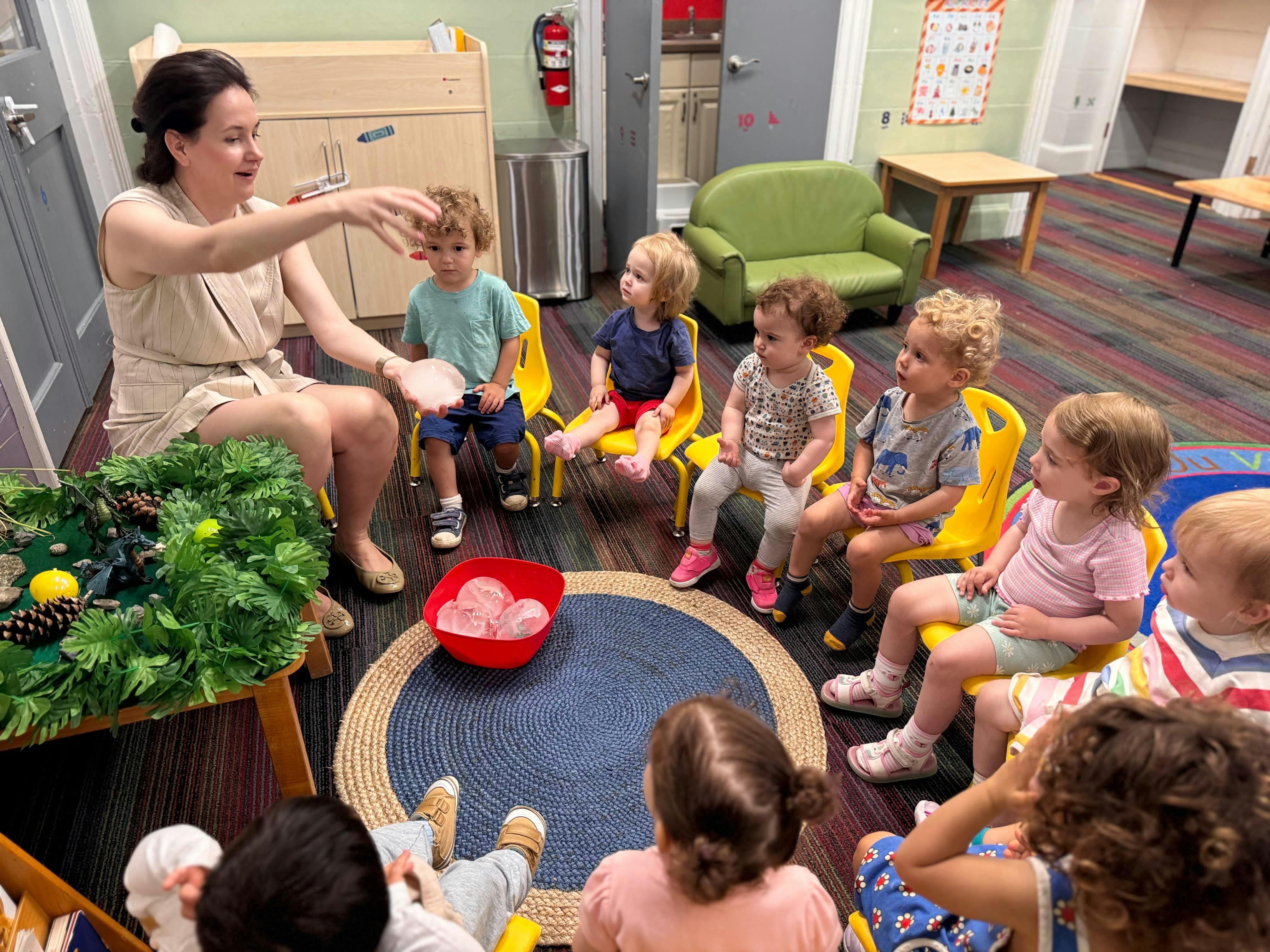 Adult leading a group of children in an activity with ice in a classroom