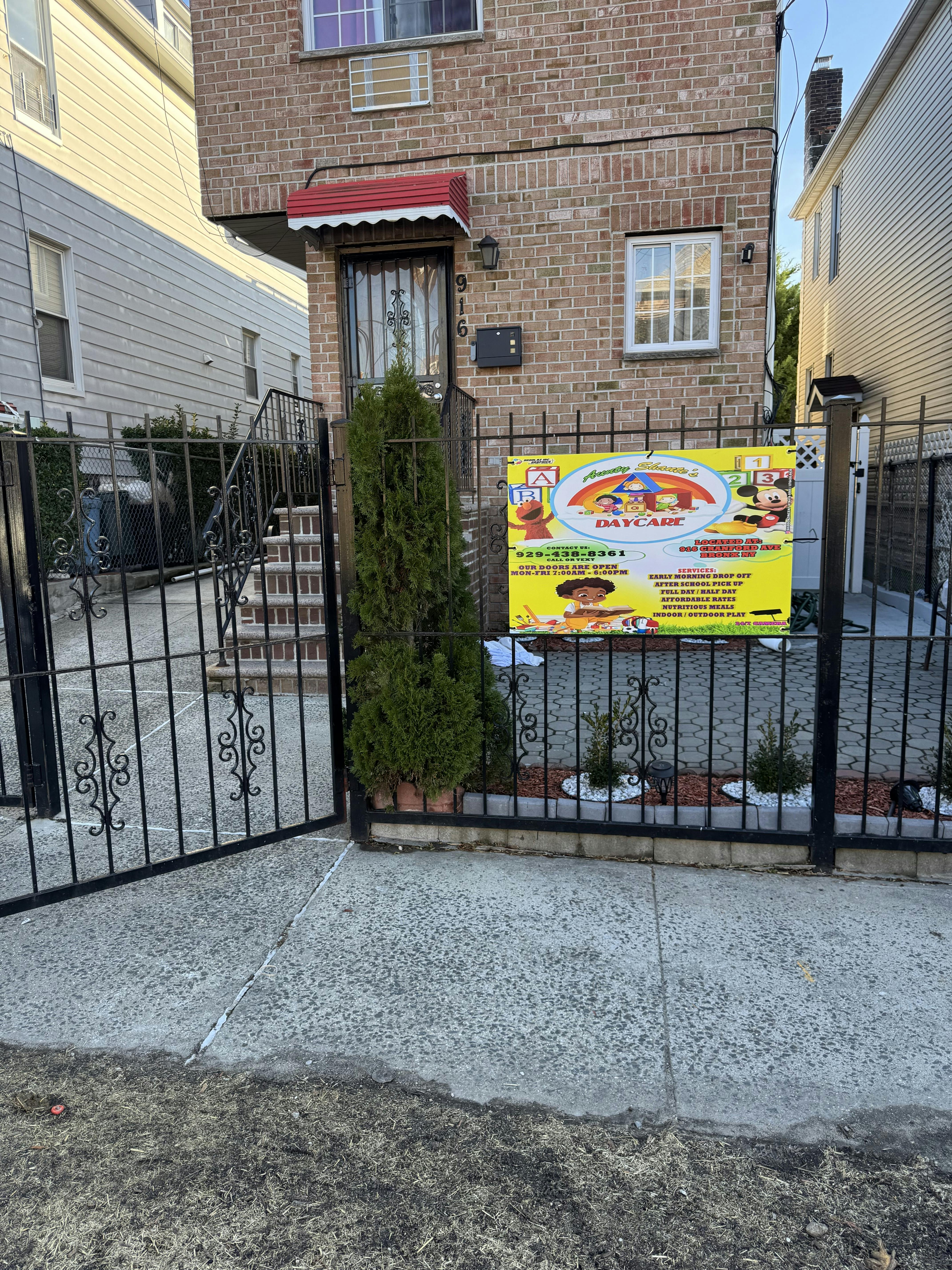 A brick building with a black gate in front and a yellow daycare sign