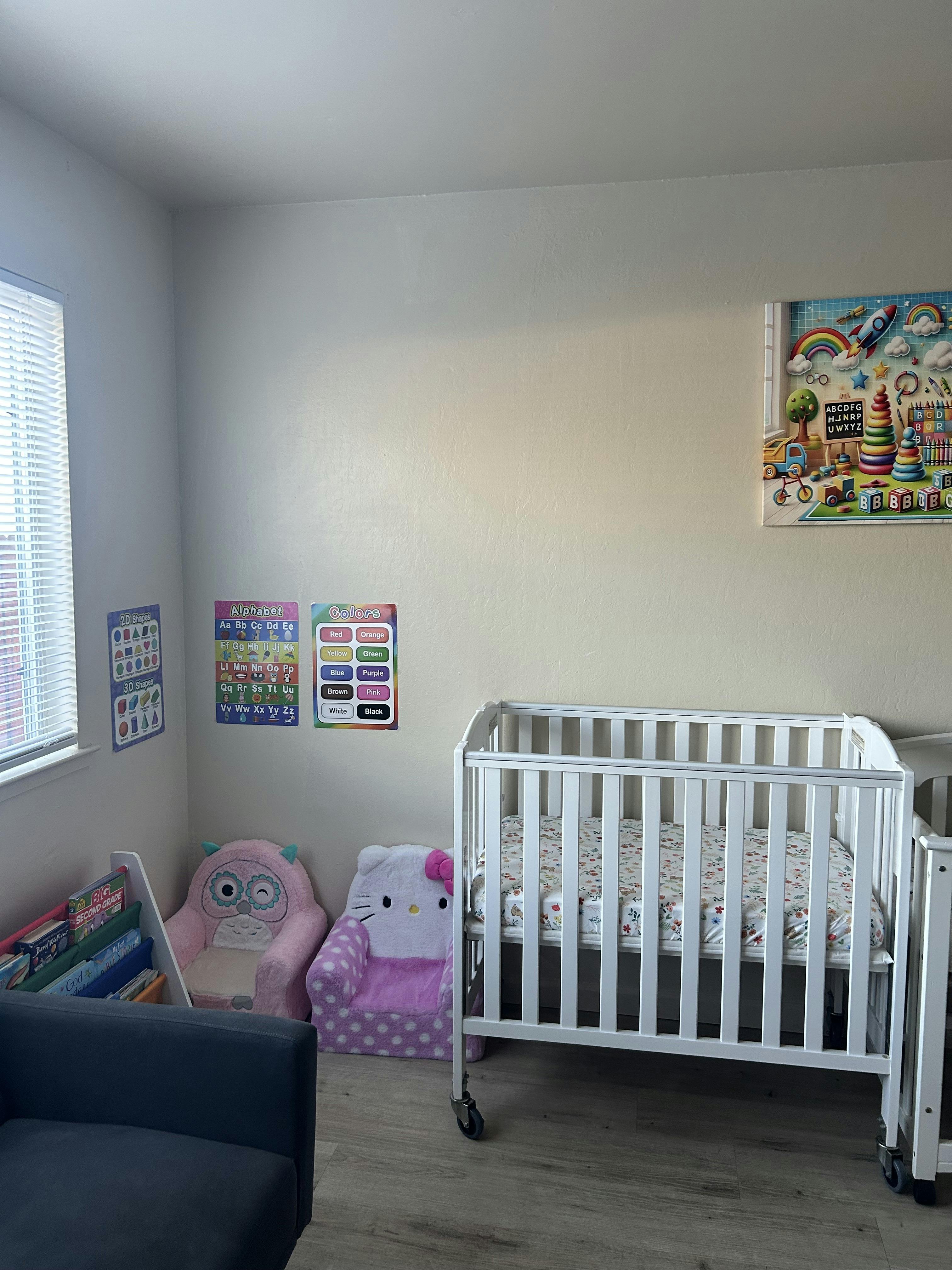 crib, small chairs, and educational posters in a room
