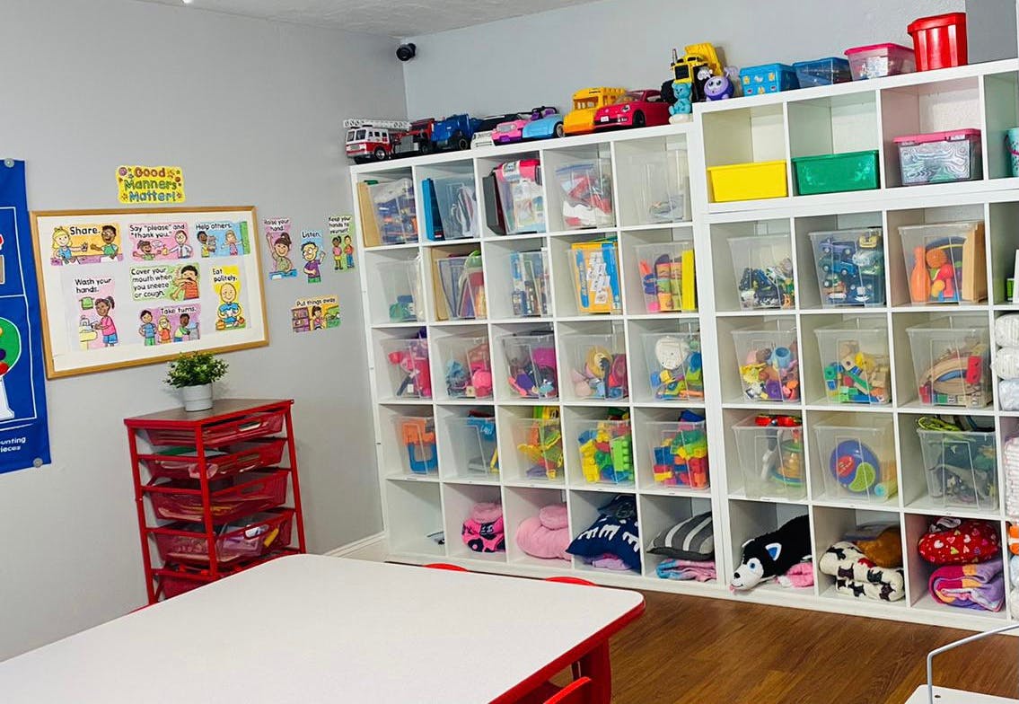 Classroom with white shelves filled with toys and a white table
