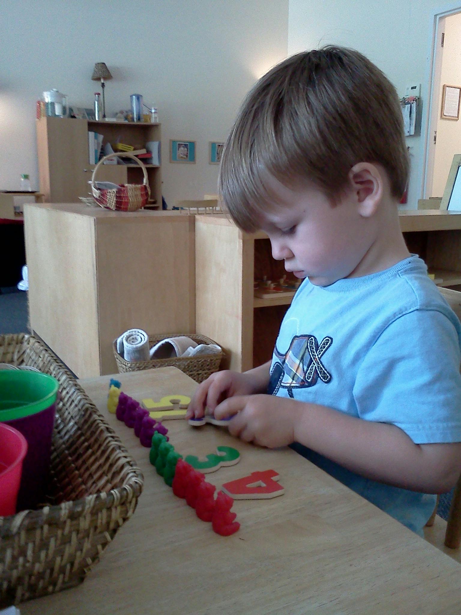 Child playing with colorful number puzzles at a table