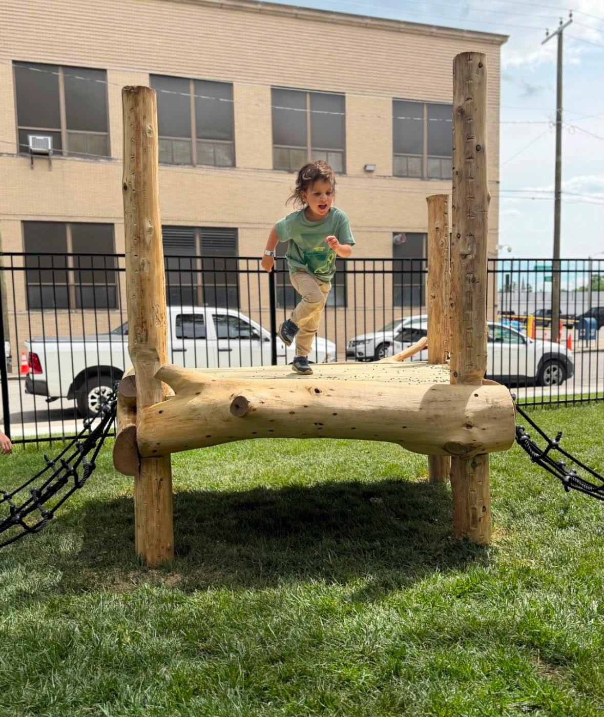 Child running across a wooden play structure in a park