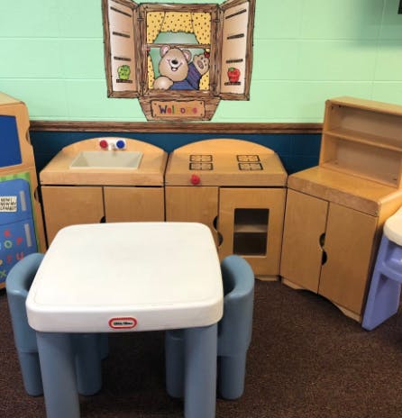 Play kitchen set with a small table and chairs in a classroom