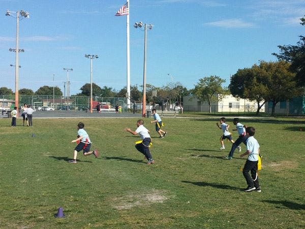 Children playing flag football on a grassy field