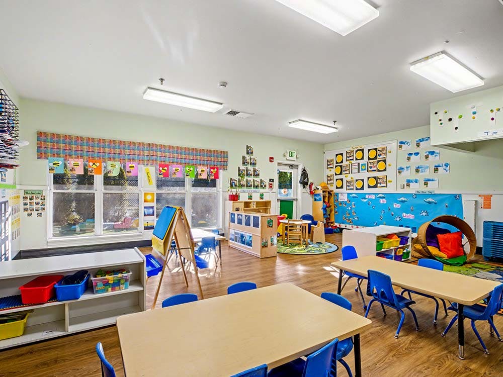 An empty childcare or preschool classroom with small tables and chairs