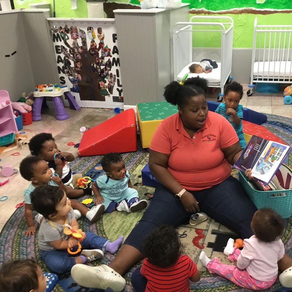 Person reading a book to a group of children sitting on a rug
