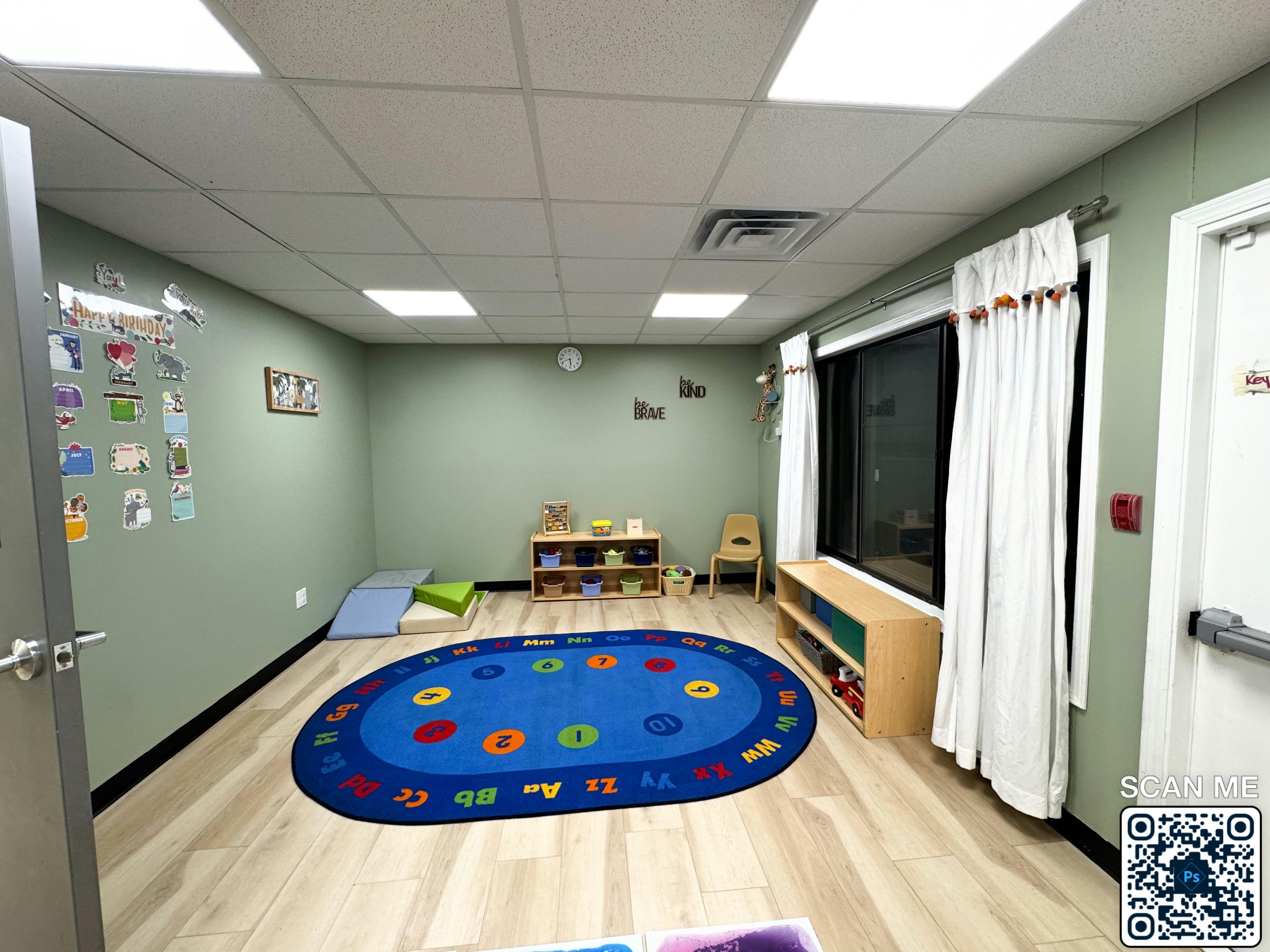 Empty classroom with a blue oval rug and small furniture