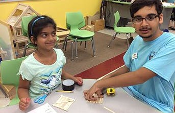 Adult and child building with small wooden blocks at a table