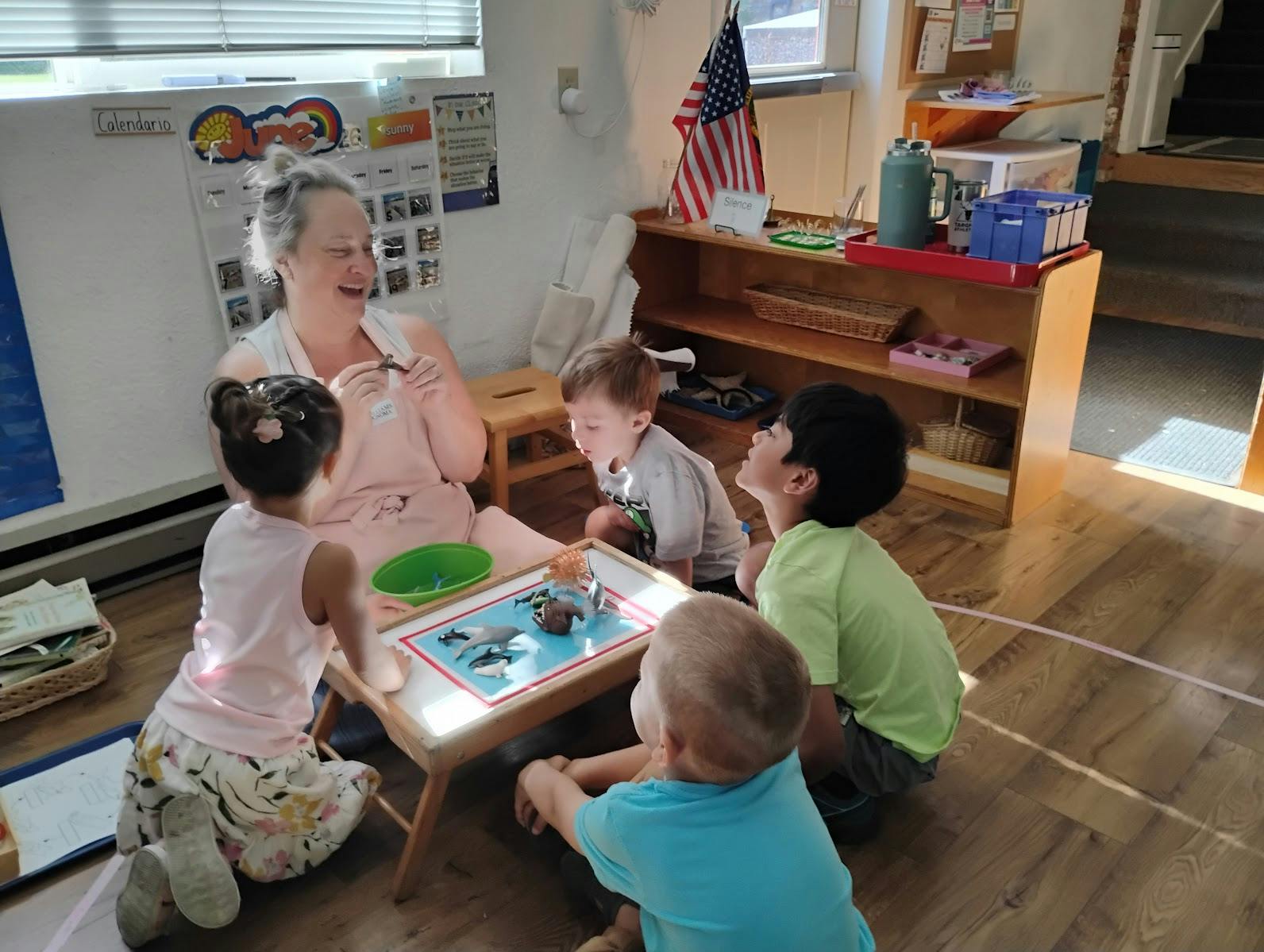 Adult and children playing with animal figurines around a small table