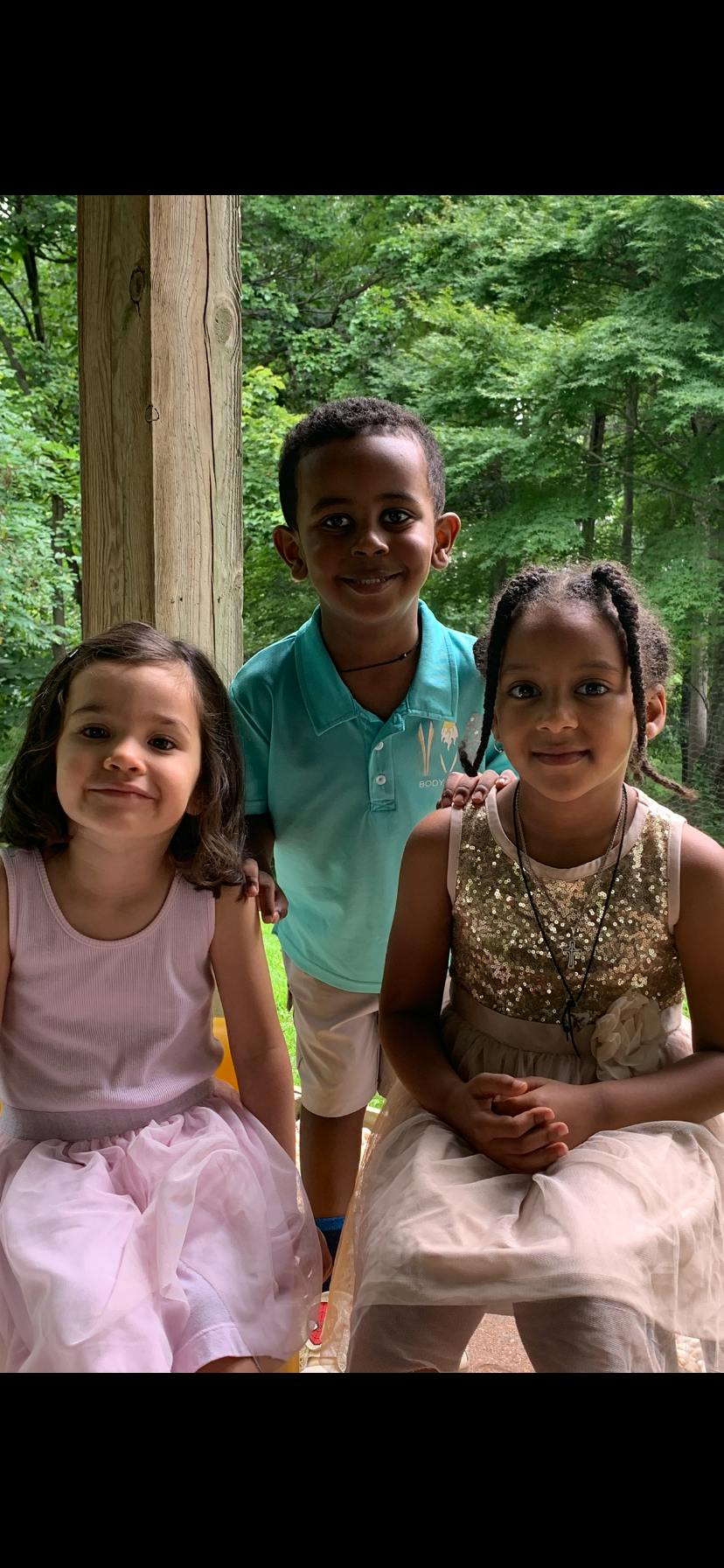 Three children posing together on a porch