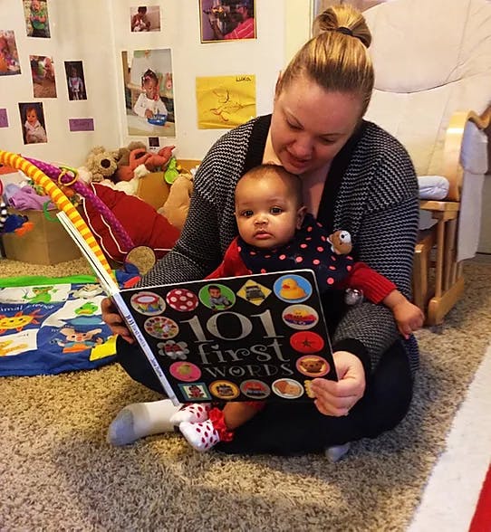 Person holding a book with a child on their lap