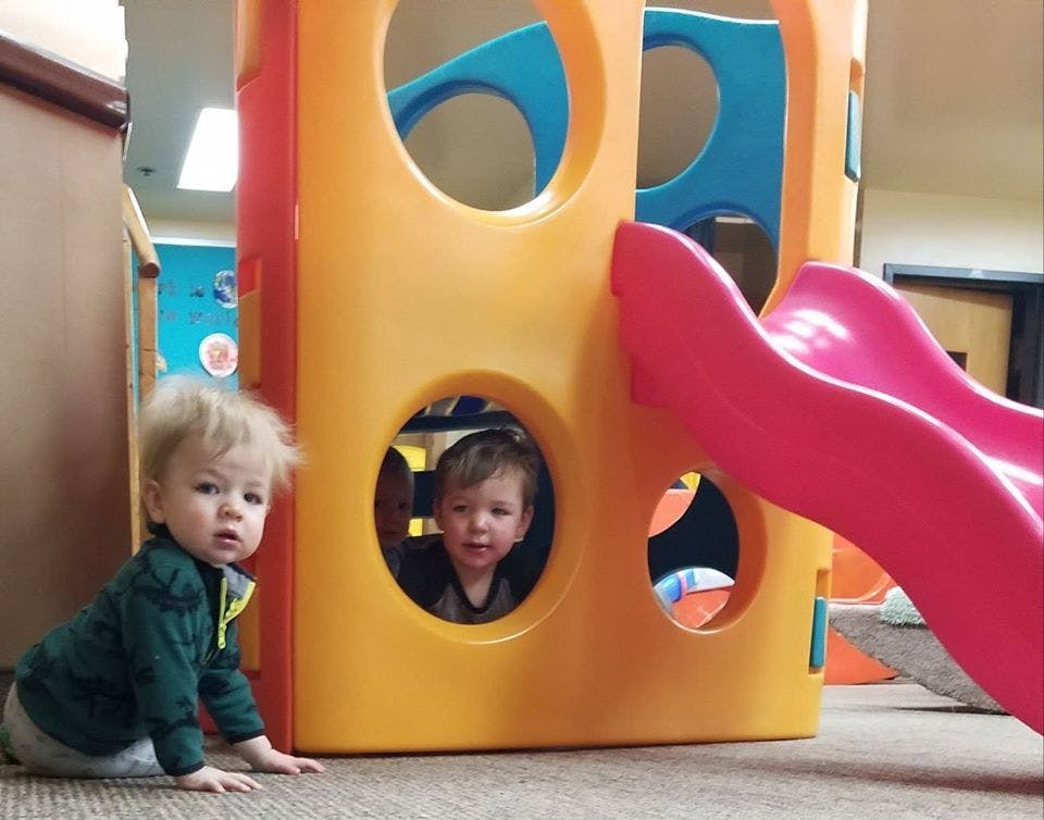 Two children playing on a colorful indoor playground structure