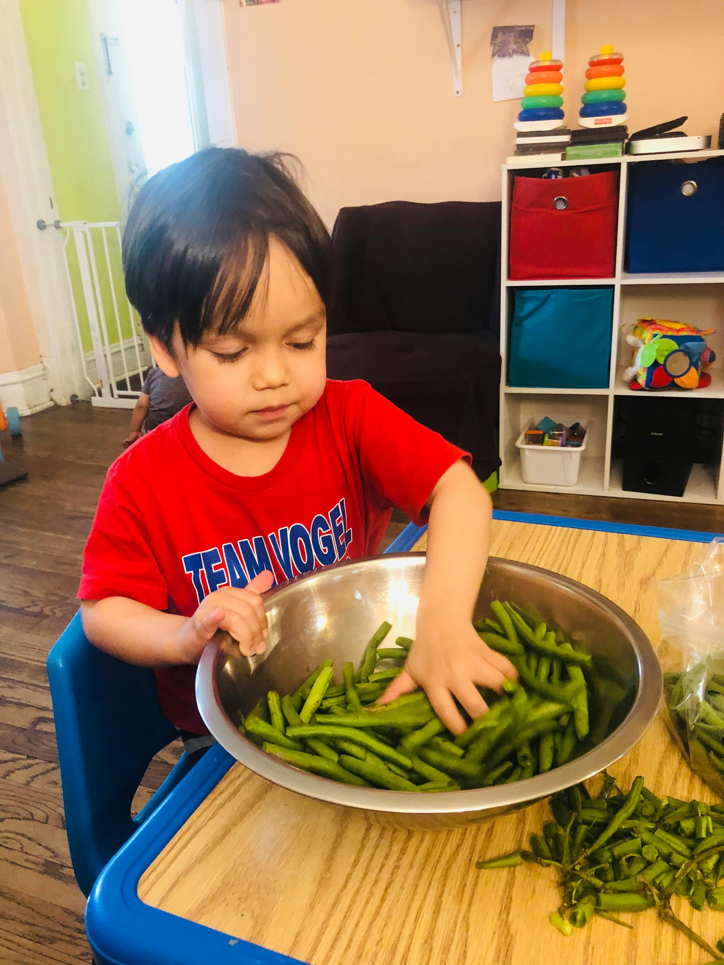 Child sitting at a table with a bowl of green beans