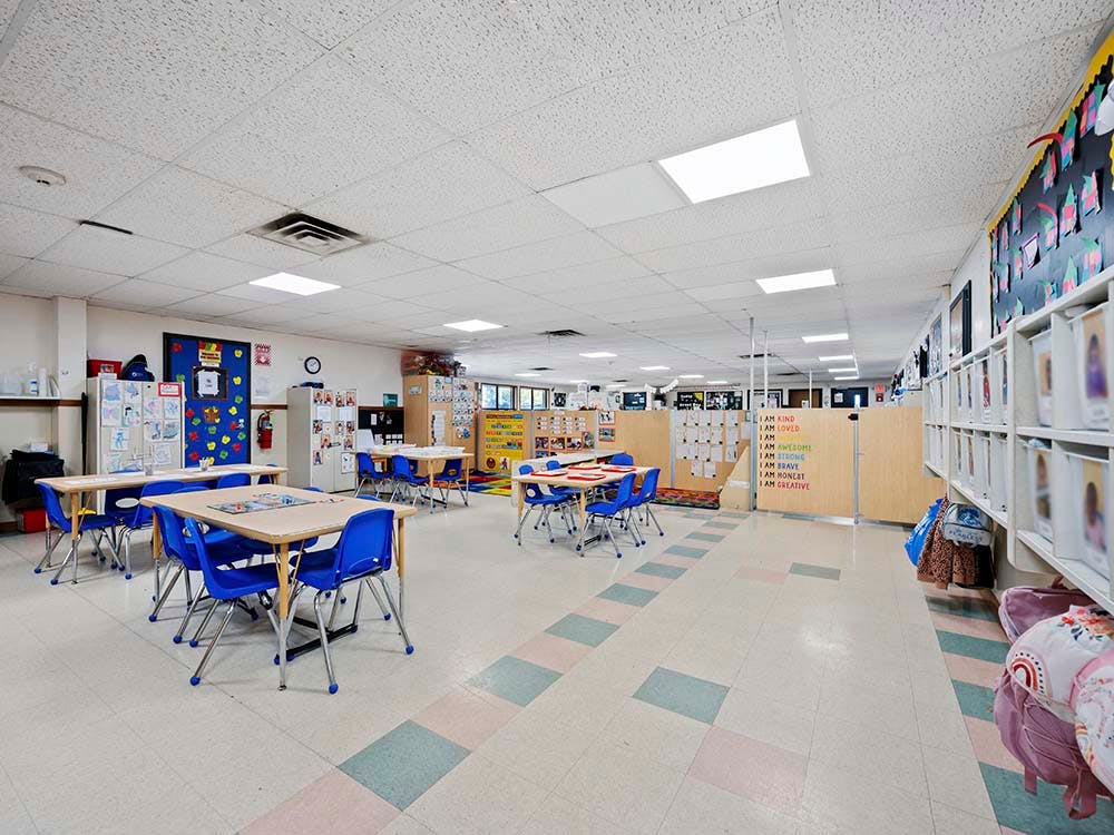 Classroom with multiple small tables and blue chairs