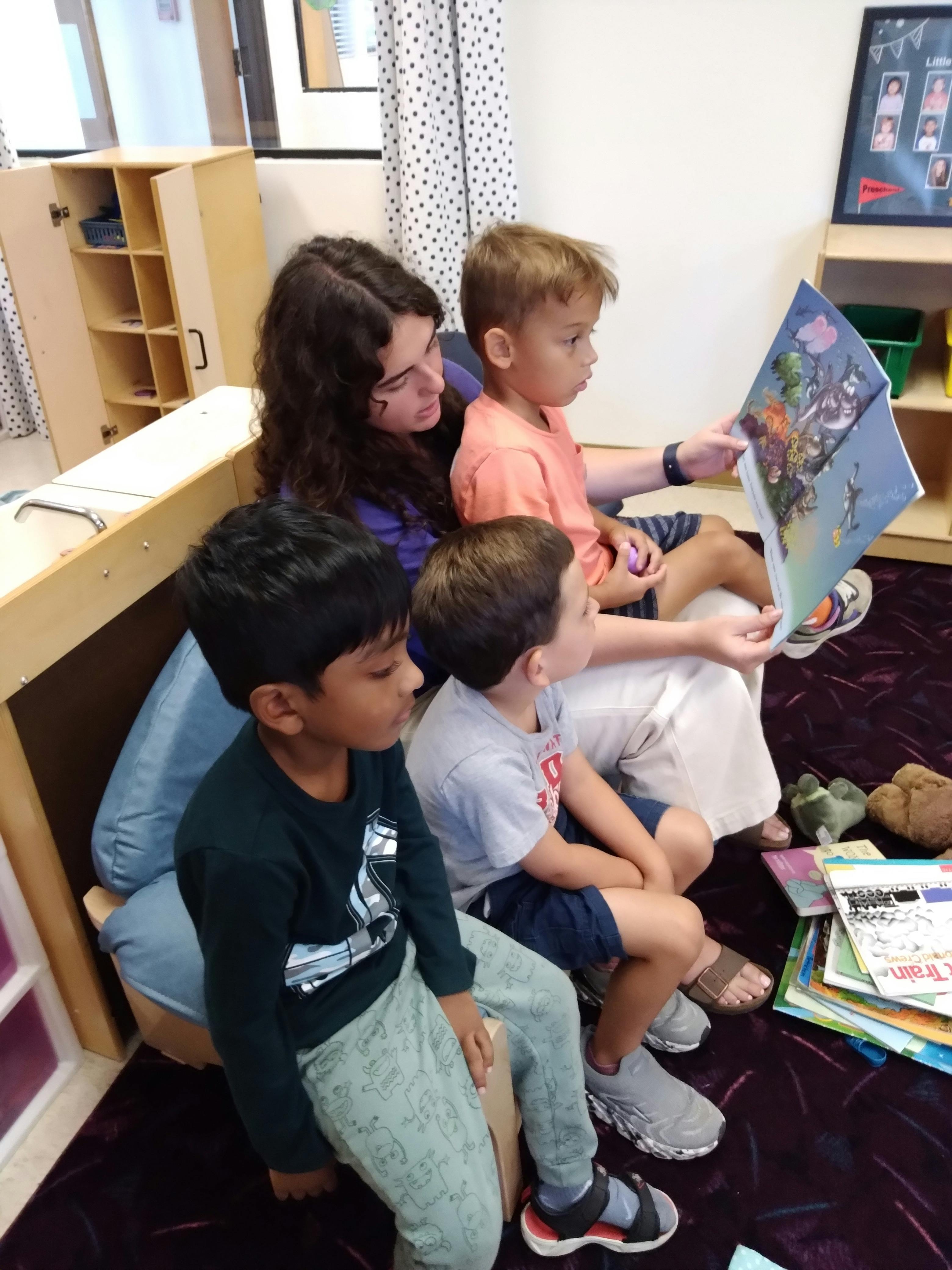 A person reading a book to a group of children in a classroom