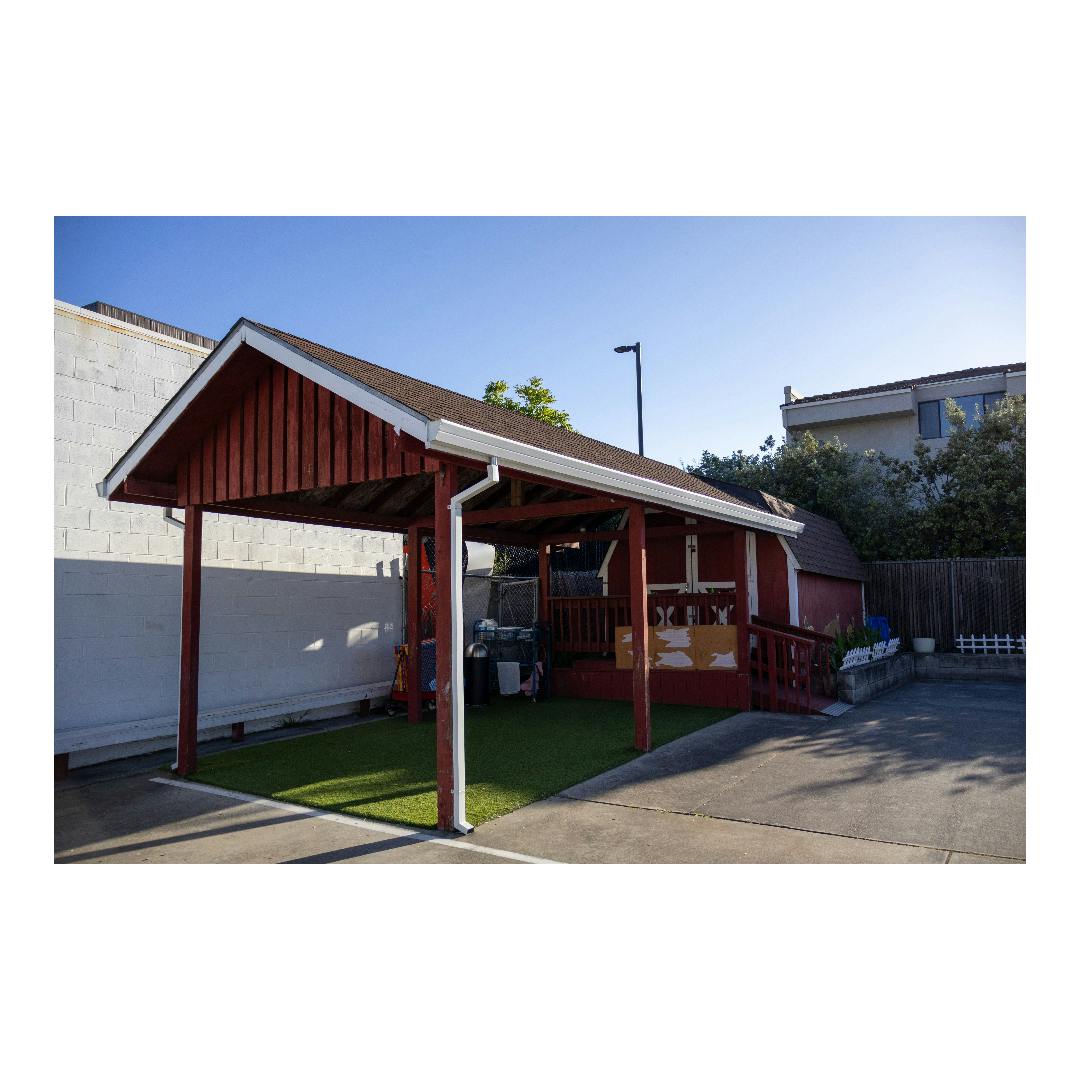 Covered patio area with artificial turf beside a small building