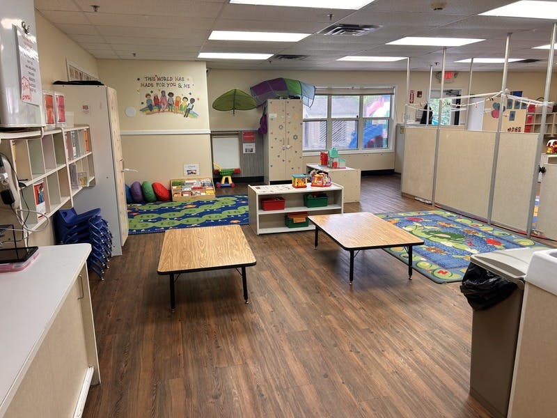 Classroom with small tables, cubbies, colorful rug, and wall decor