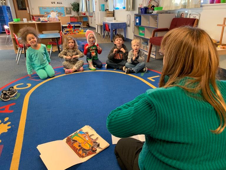 Adult reading a book to children in a classroom