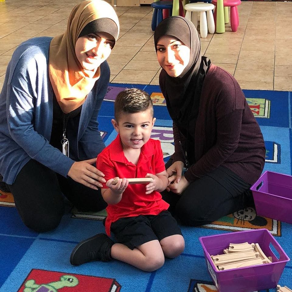 Two people kneeling with a child holding a wooden block