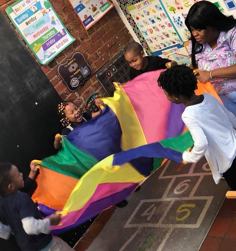 Adult and children playing with a colorful parachute