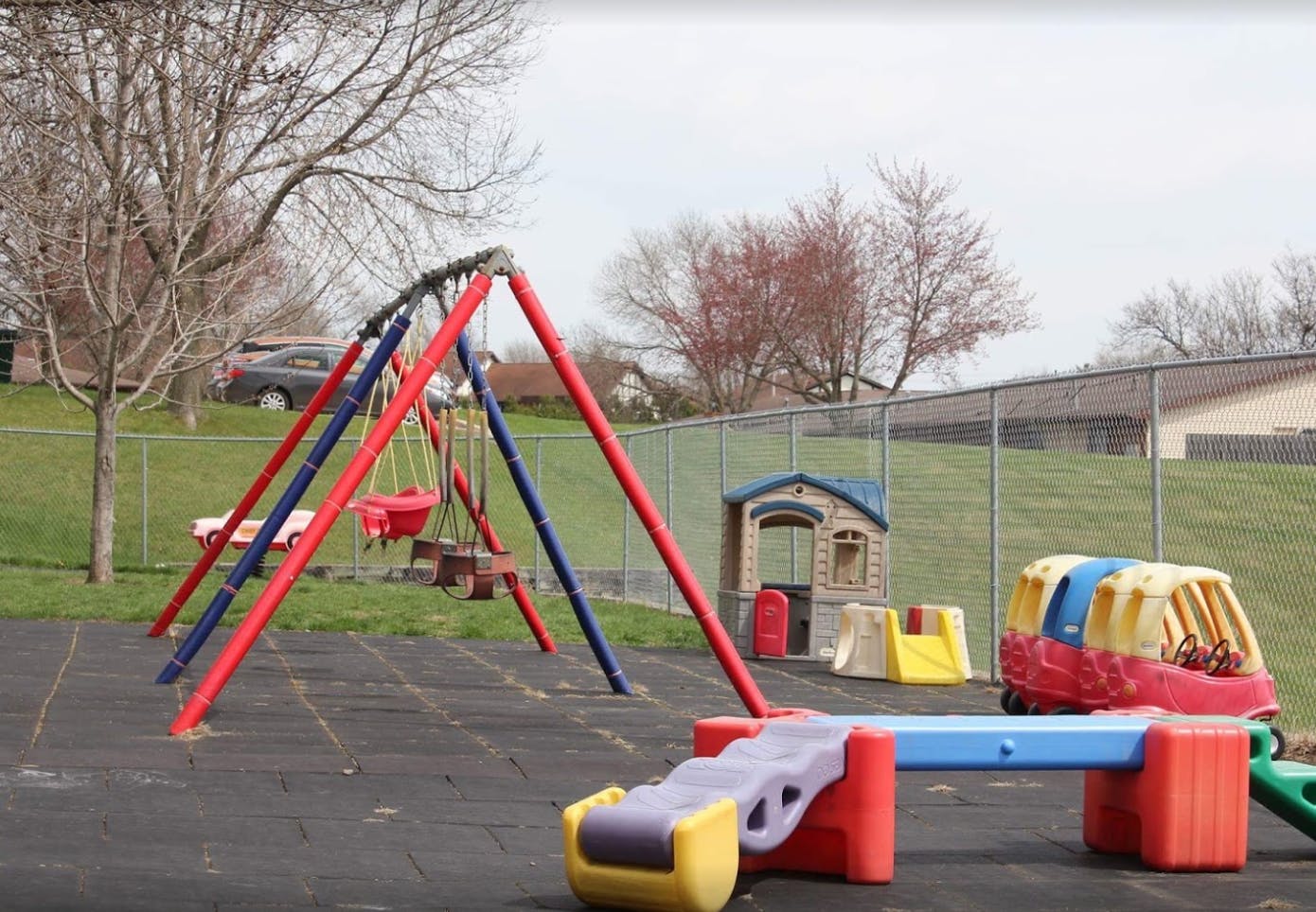 Playground with swings, a playhouse, and other colorful play equipment