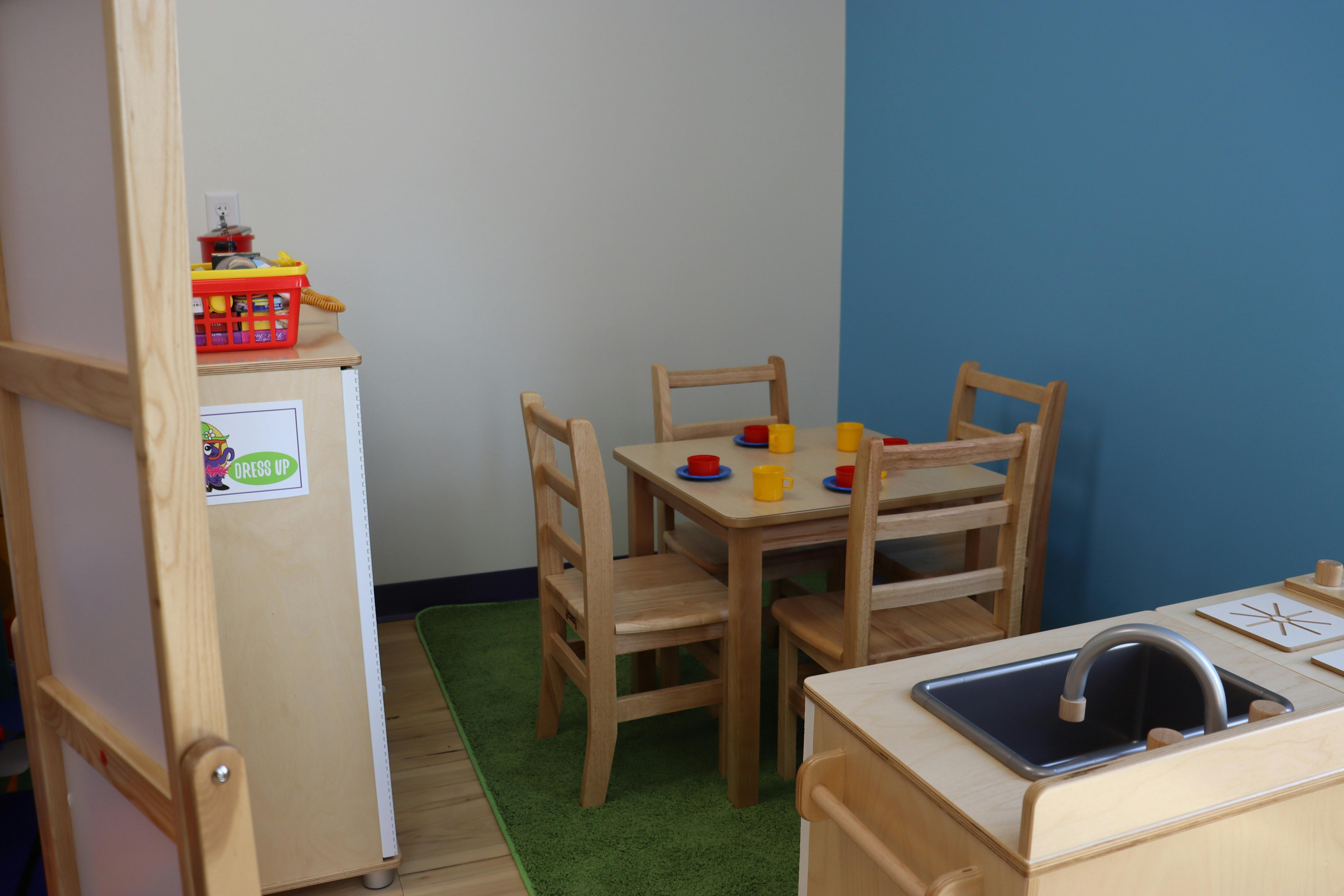 Child-sized table and chairs with colorful cups and saucers in a classroom