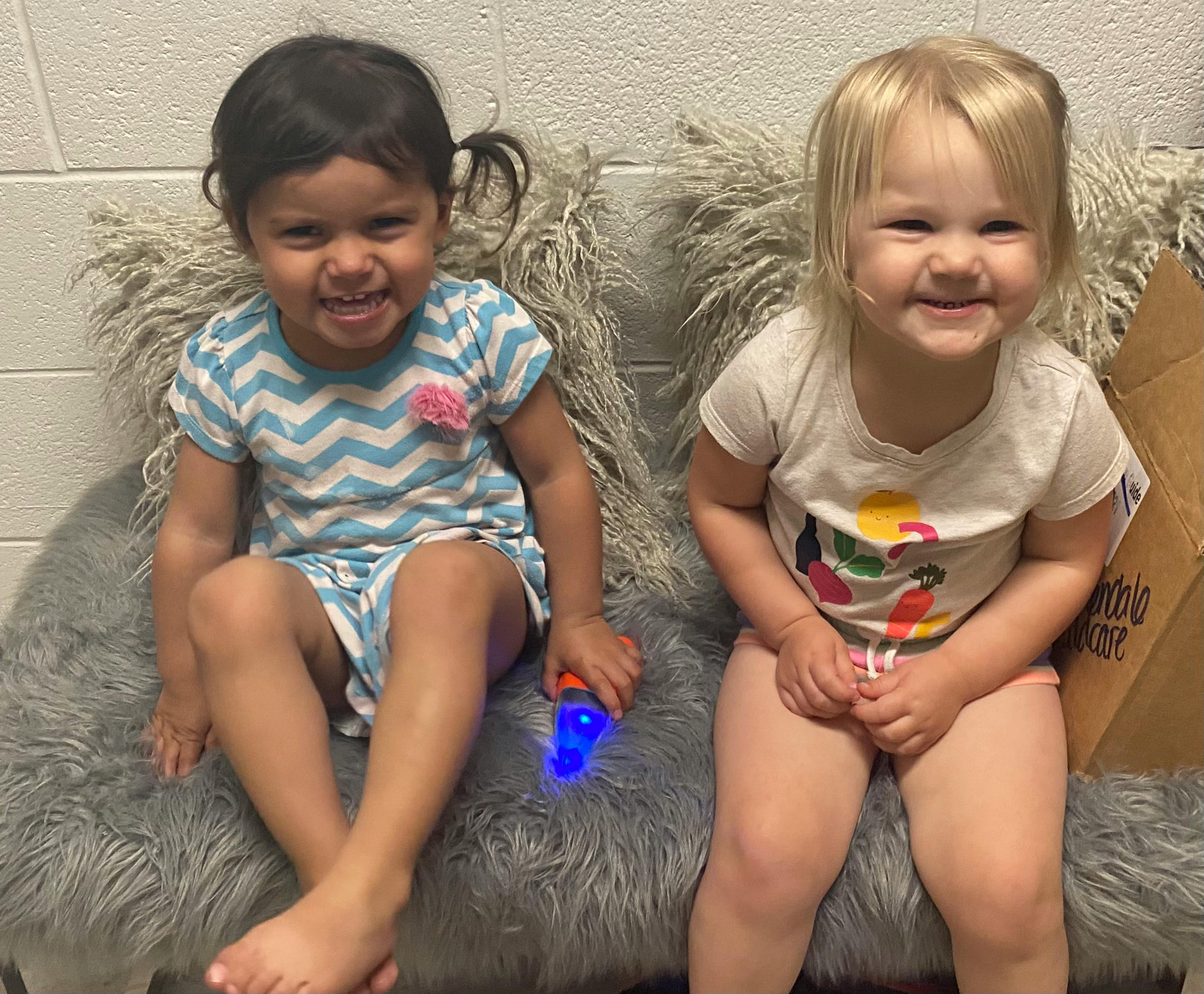 Two children sitting on a furry bench