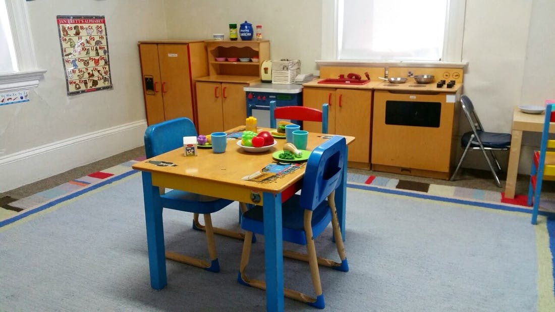 Playroom with small table and chairs set for a meal, and a toy kitchen