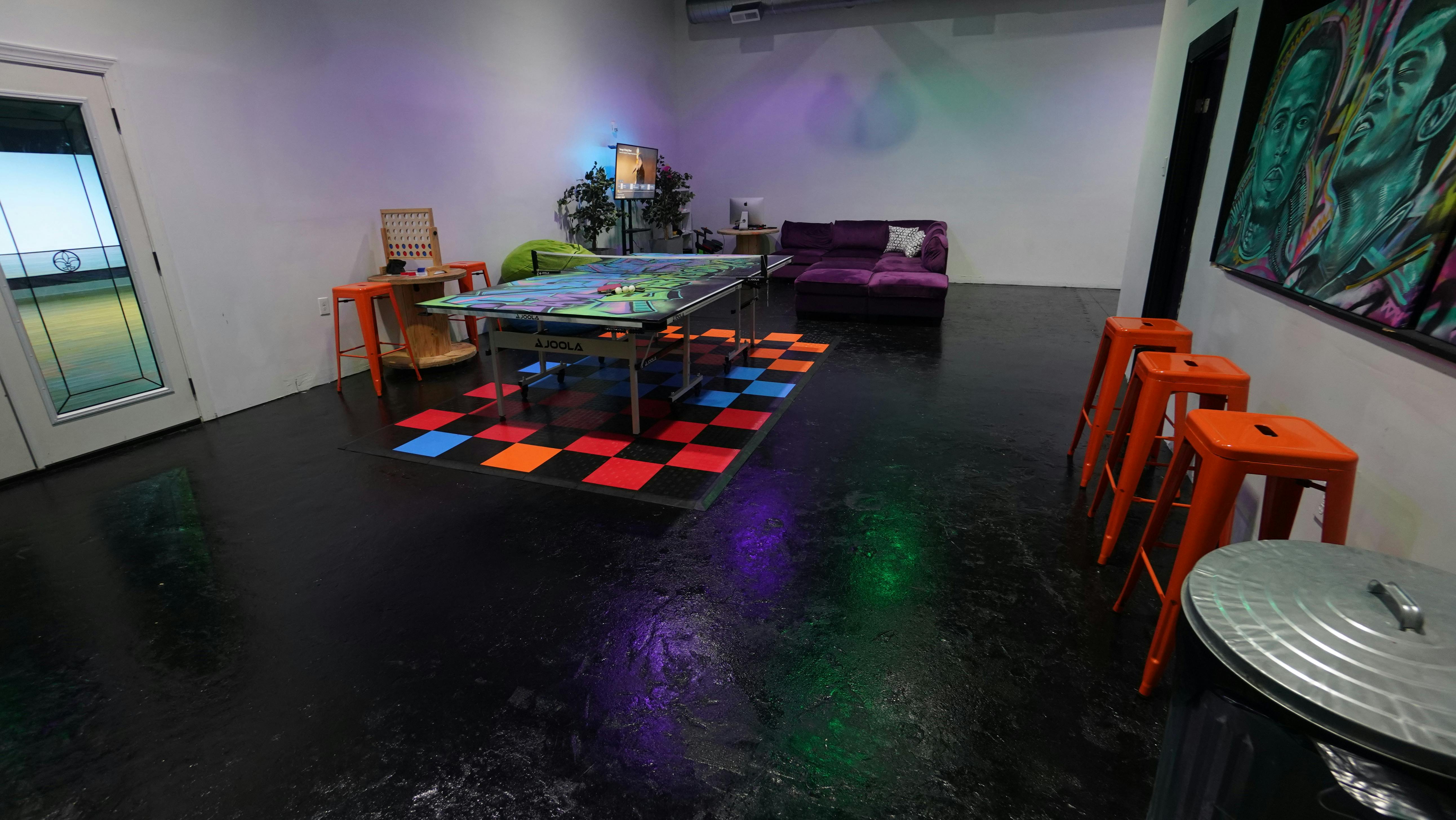 Room with a table, chairs, and a colorful checkered floor pattern