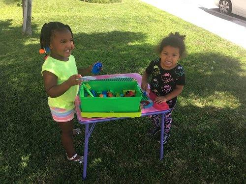 Two children playing with toys at a small table outdoors