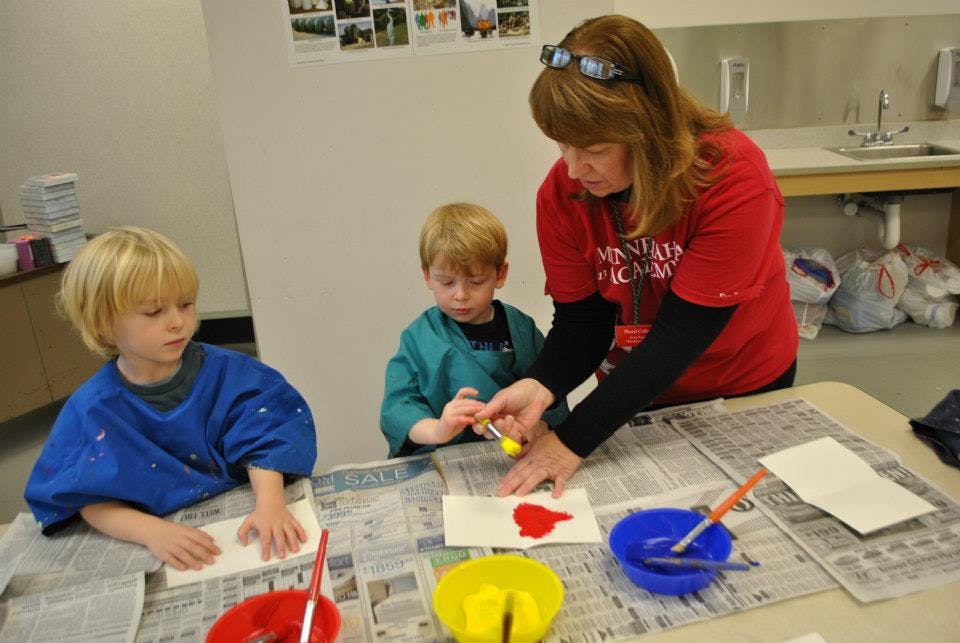Adult and two children painting at a table
