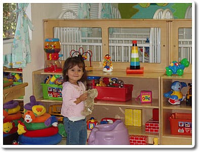 Child holding a stuffed animal in a playroom