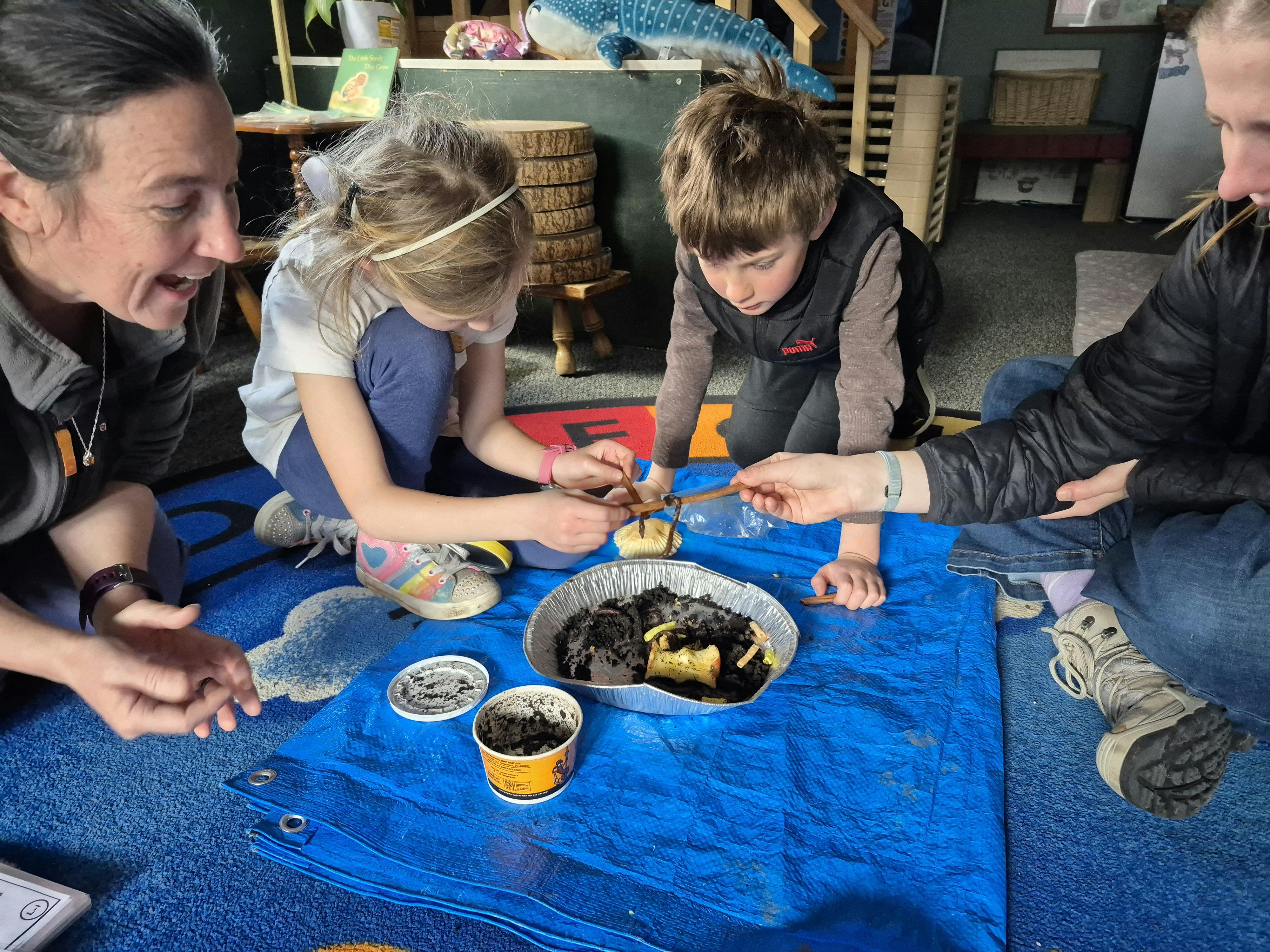 Two adults and two children planting seedlings in small pots