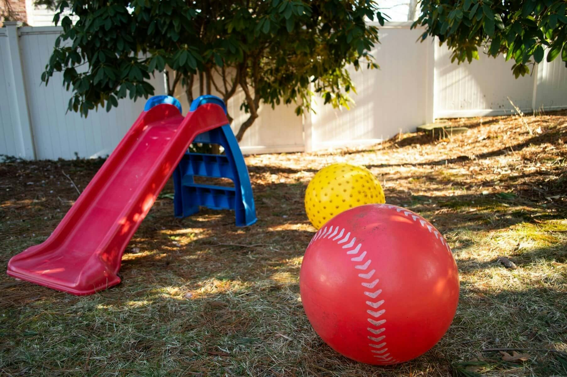 Red slide and two large balls on grass